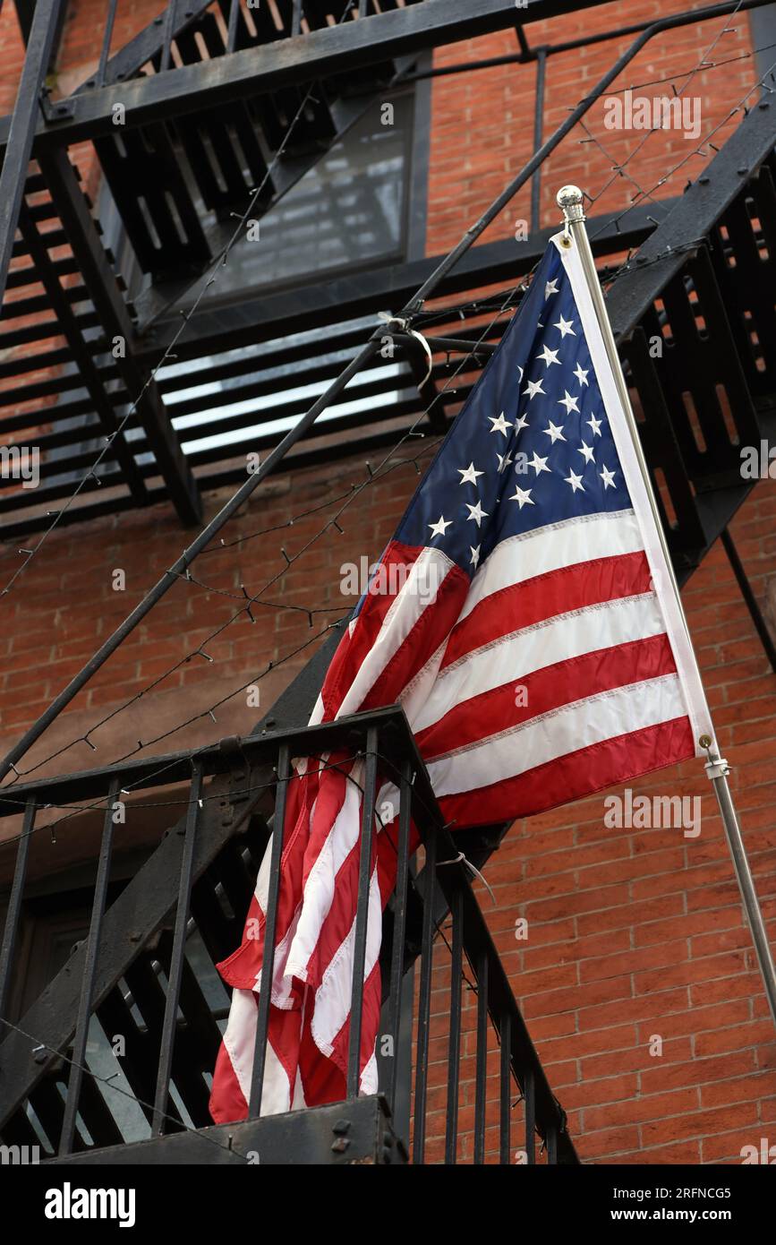 Eine amerikanische Flagge mit Sternen und Streifen hängt über der Feuertreppe in New York City. Stockfoto