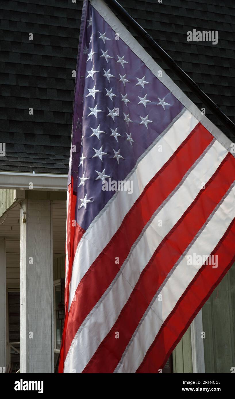 Vor einem Haus hängt eine amerikanische Flagge mit Sternen und Streifen Stockfoto