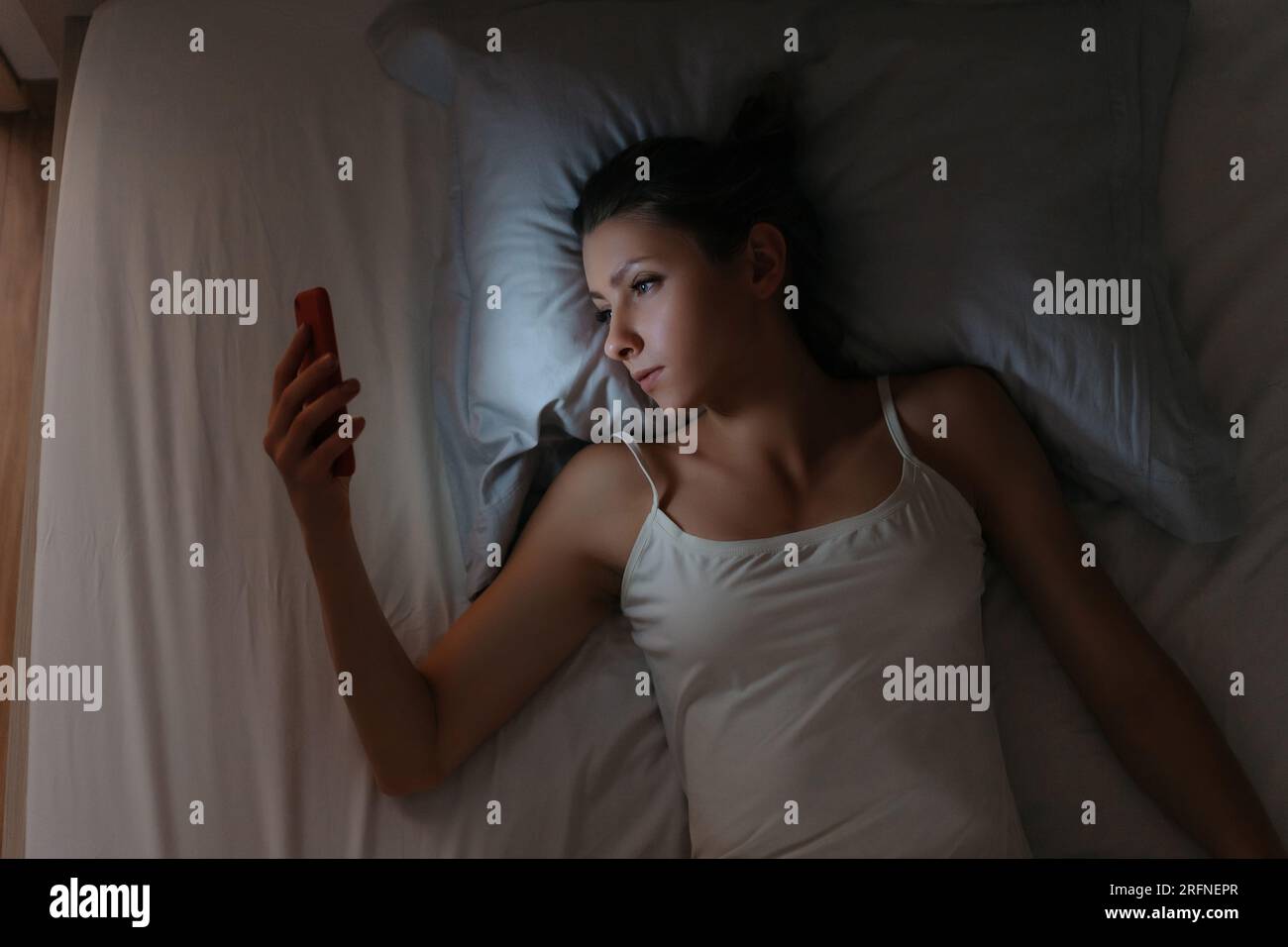 Das Mädchen kann nachts nicht schlafen und ihr Handy im Bett checken. Smartphone-Abhängigkeit. Intermet und soziale Netzwerke Suchtbegriff Stockfoto