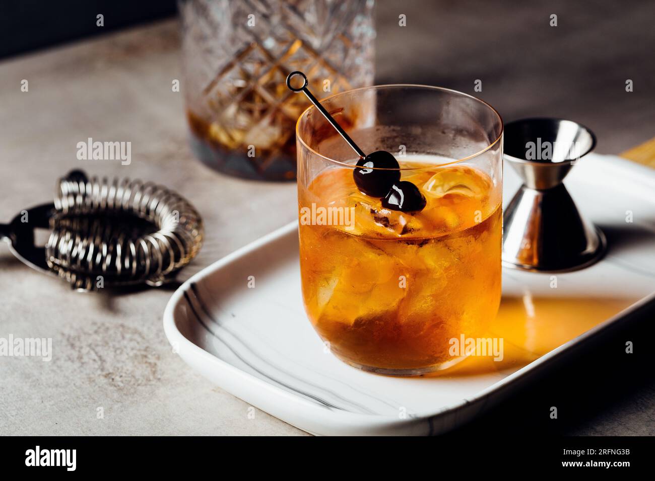 Alkoholisches Manhattan Drink on the Rocks Bourbon Whiskey und garnieren mit Maraschino Kirschen Stockfoto