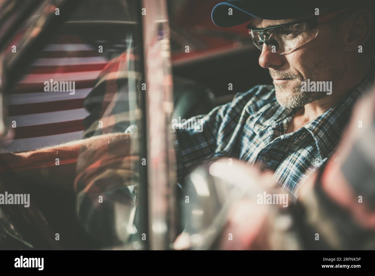 Amerikanischer Automechaniker hinter dem Lenkrad des Fahrzeugs auf der Suche nach potenziellen Problemen Stockfoto