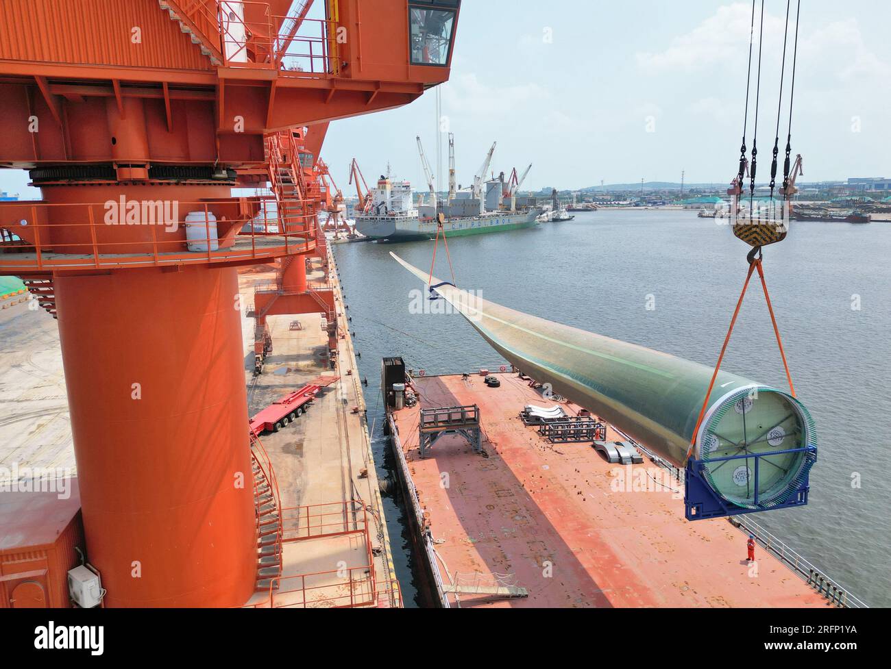 YANTAI, CHINA - 4. AUGUST 2023 - Ein Kran hebt B1260A supergroße Offshore-Windturbinenblätter von einem Frachtschiff im Penglai Port Area von Yantai Po Stockfoto