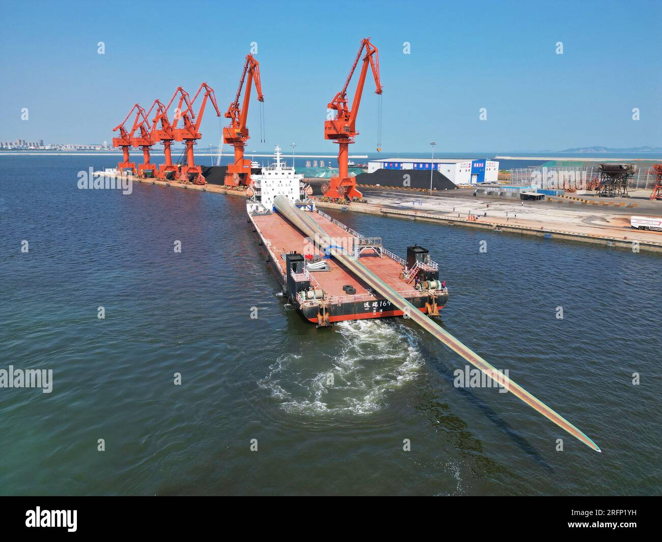 YANTAI, CHINA - 4. AUGUST 2023 - Ein Frachtschiff mit B1260A ultragroßen Offshore-Windturbinenschaufeln legt im Penglai Port Area im Yantai Port, Shan an an Stockfoto