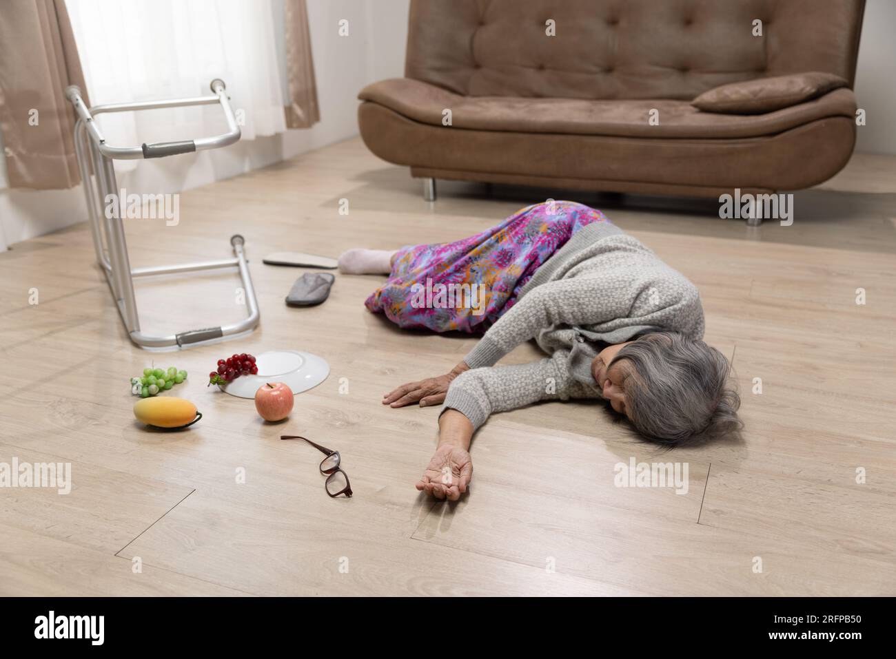 Seniorin fällt wegen Bluthochdruck im Wohnzimmer. Stockfoto