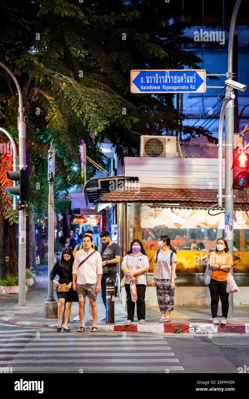 Fußgänger warten an einer Zebraüberquerung in der geschäftigen Innenstadt von Silom in Bangkok City, Thailand. Stockfoto