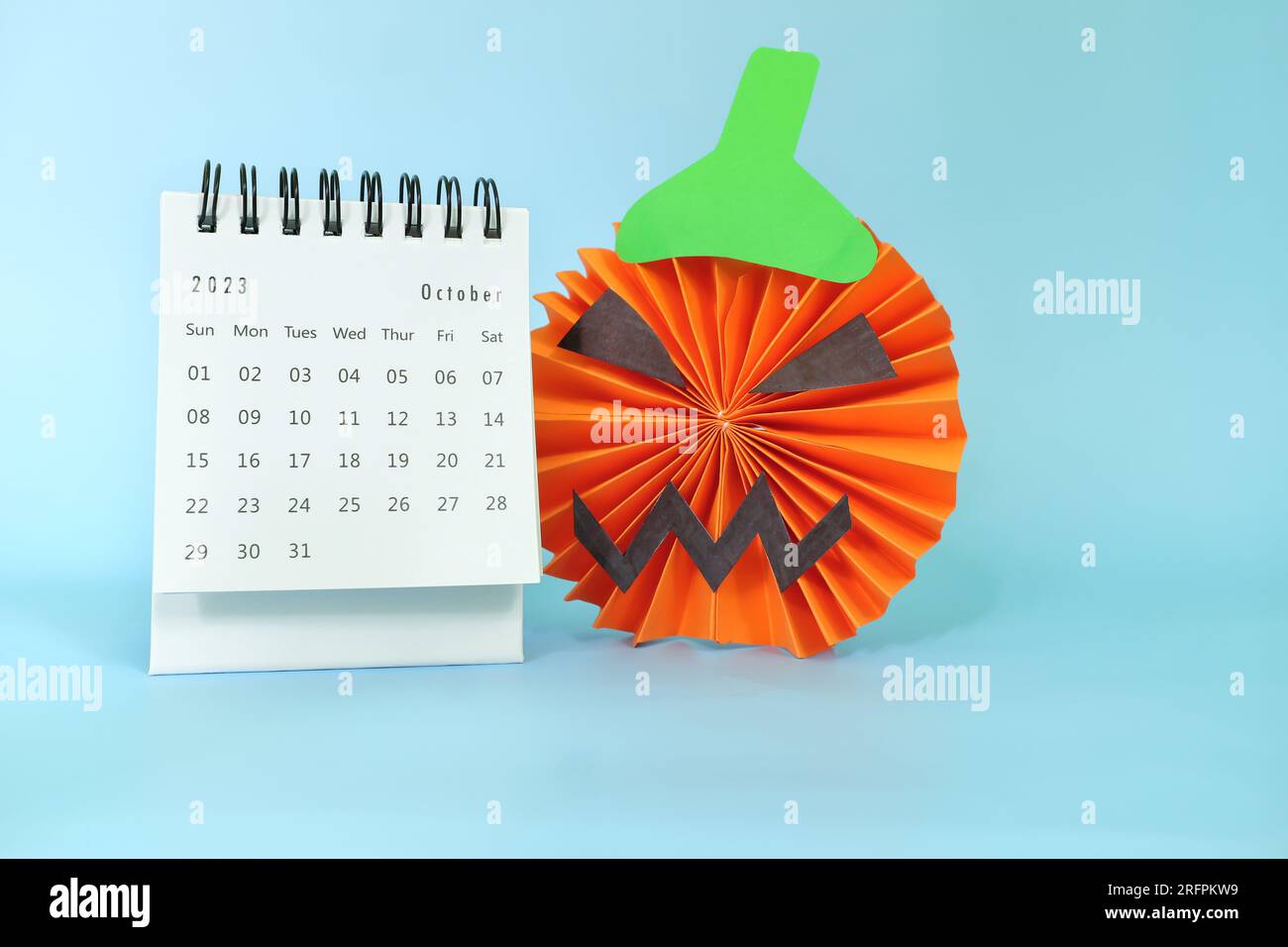 Ausgewählter Fokus des Tischkalenders vom Oktober 2023 mit Jack o Laterne Kürbis Dekoration auf blauem Hintergrund mit Kopierbereich. Halloween-Feier. Stockfoto