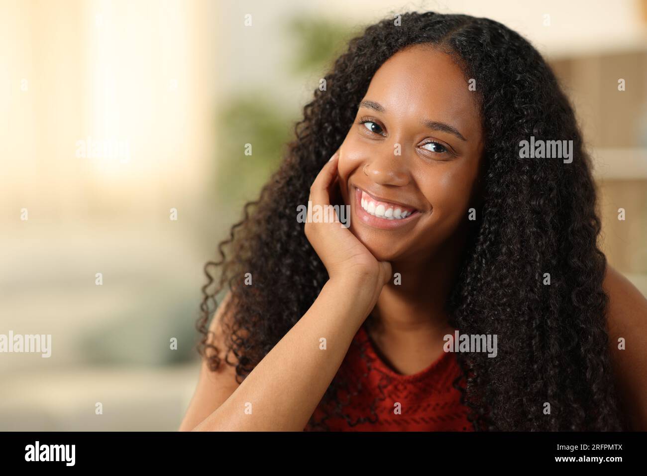 Schönheitsporträt einer glücklichen schwarzen Frau, die zu Hause mit weißen Zähnen posiert Stockfoto