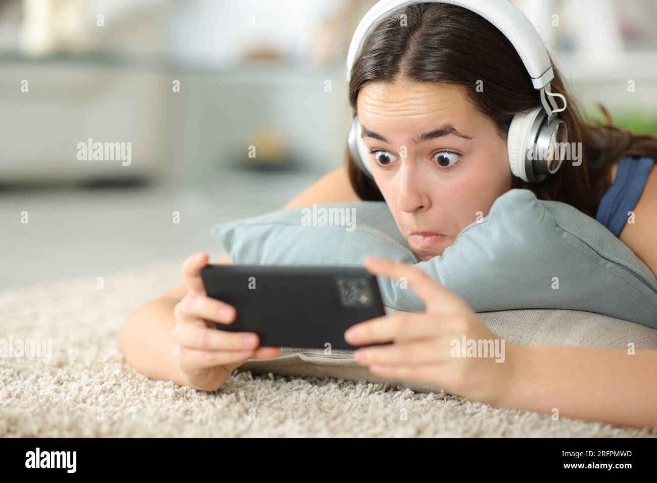 Verblüffte Frau, die zu Hause ein Heaphon trägt und Online-Inhalte ansieht Stockfoto