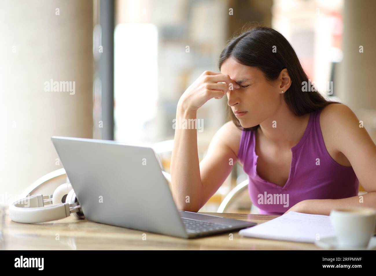 Student leidet unter Augenschmerzen E-Learning mit Lapeop auf einer Barterrasse Stockfoto