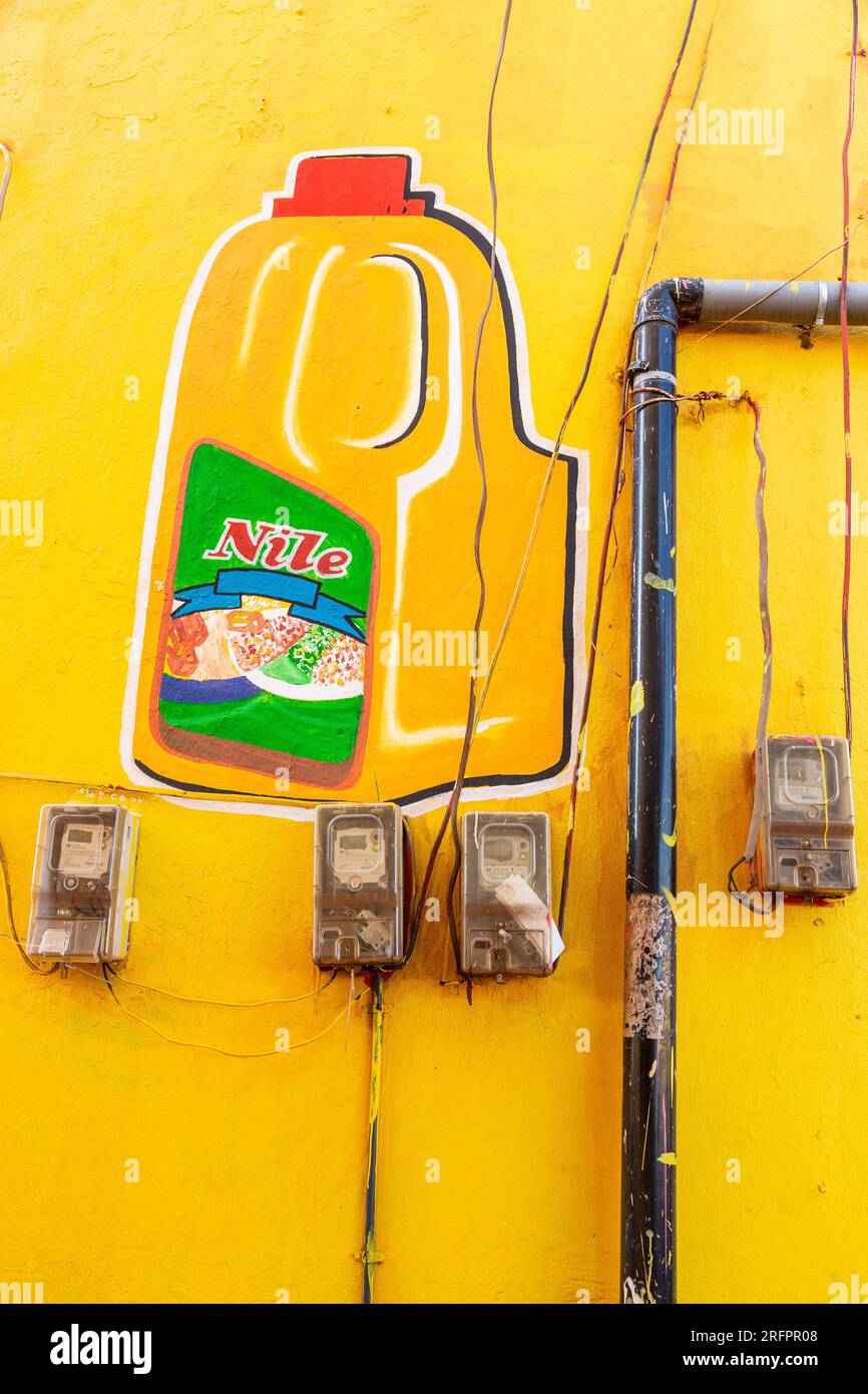 Werbung auf eine gelbe Wand gemalt. Elektrische Zähler und Evakuierungsleitung. Jinja, Uganda. Stockfoto