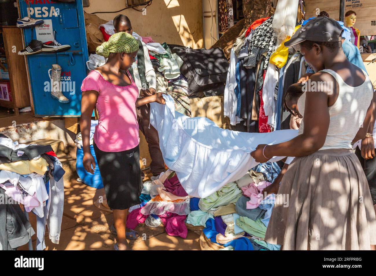 Im Schatten, am Rande des Marktes, bewerten Frauen Blätter, die von einem Clothier gebracht werden. Jinja, Uganda. Stockfoto