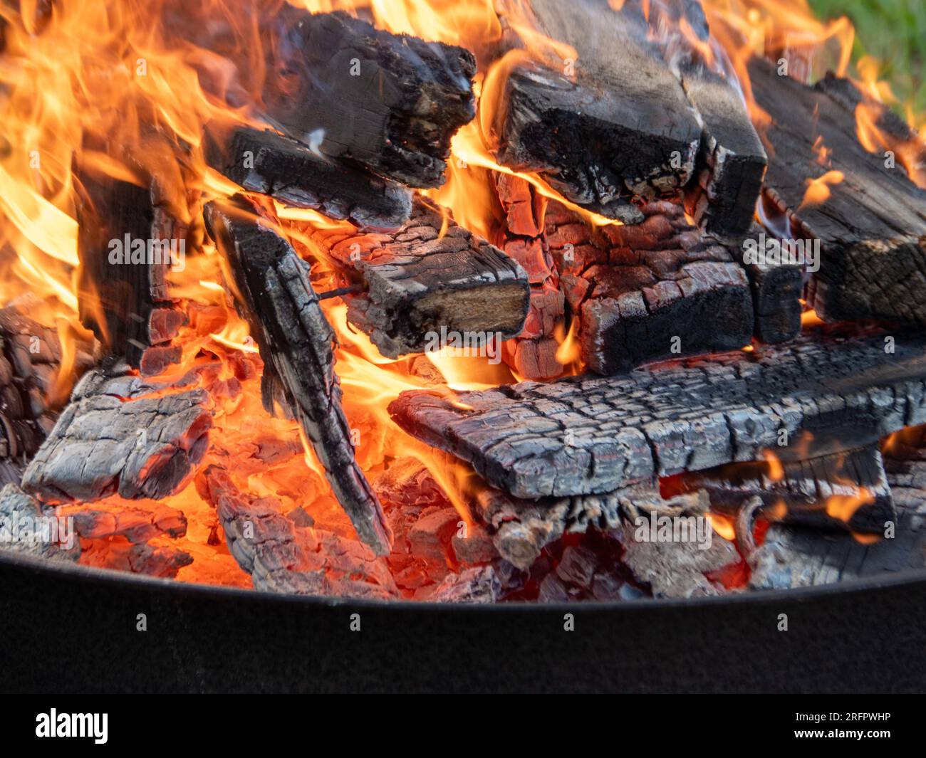 Holz brennt in einer Feuerstelle, orangefarbene Flammen und Glut Stockfoto