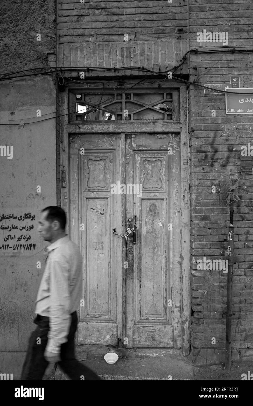Alte Holztür in der Nähe der Straße, der Mann, der vor einem historischen Objekt in Tajrish, Teheran, Iran läuft Stockfoto
