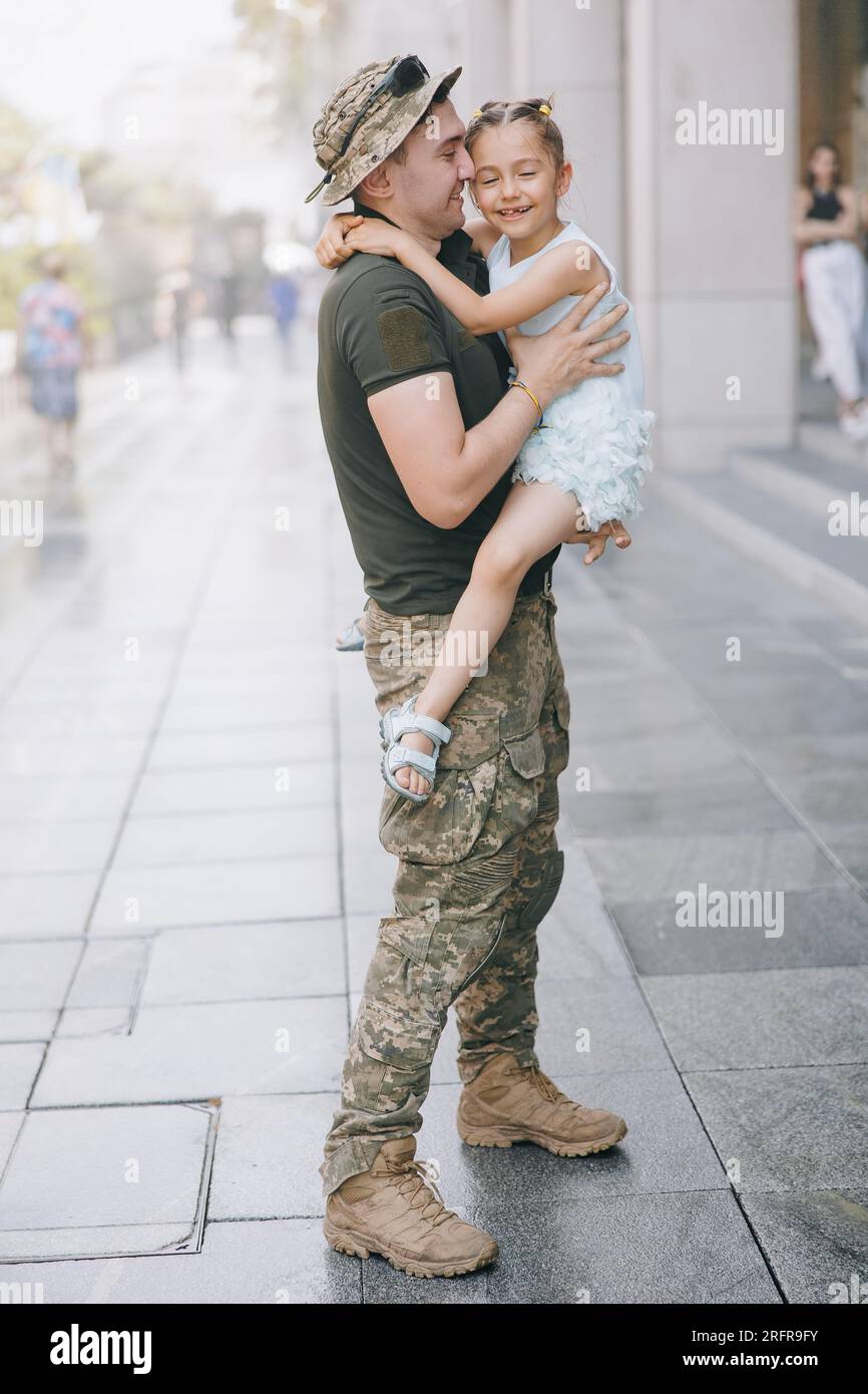 Der aus dem Krieg zurückkehrende ukrainische Soldat trifft seine kleine Tochter und freut sich über sie. Krieg in der Ukraine. Russische Militärinvasion in der Ukraine. Krieg Stockfoto