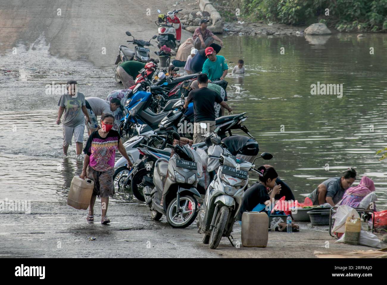 Bogor, Indonesien - 05. August 2023: Aktivitäten von Einwohnern in Bogor, Wäsche waschen und Motorräder im Fluss Stockfoto