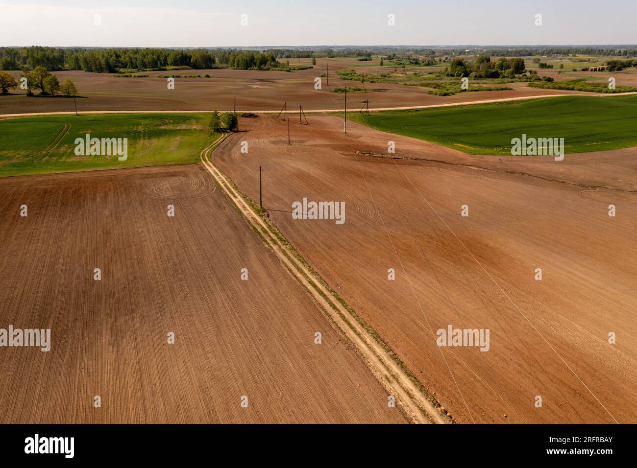 Drohnenfotografie von landwirtschaftlichen Feldern und Strommasten und -Linien am Frühlingssonntag Stockfoto