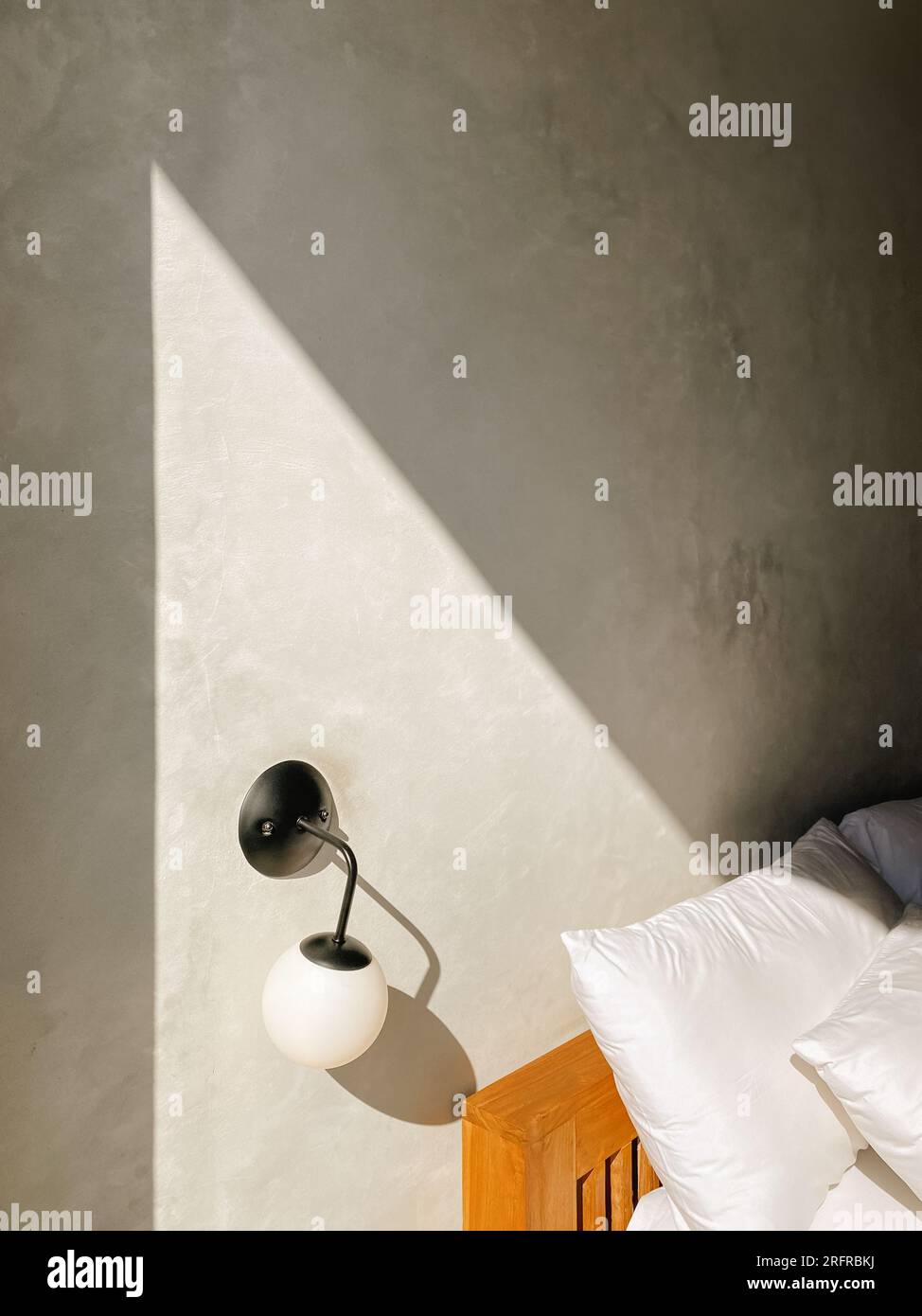 Klassische runde Form auf der Betonwand im Sonnenfleck in der Nähe des Bettes Stockfoto