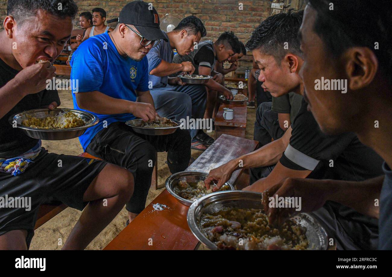 25. Juni 2023, Churachandpur, Manipur, Indien: Stammesfreiwilligen aus der Kuki-Zo-Gemeinde essen zu Mittag, nachdem sie von einer Nachtwache gegen die Meiteis in Churachandpur im nordöstlichen indischen Staat Manipur zurückgekehrt sind. Um ihre Selbstverteidigungspflichten effektiv zu erfüllen, werden die Freiwilligen des Dorfes Kuki rigoros geschult. In diesem Prozess lernen sie die grundlegenden Fähigkeiten des Handhabens von Schusswaffen, wie man ein Gewehr benutzt, wie man es nachlädt, wie man sich vor dem Feind versteckt, wie man ein Messer im Nahkampf mit dem Feind benutzt, was als letztes Mittel benutzt werden kann usw. Diese jungen Freiwilligen sind im Alter von 13 t tätig Stockfoto