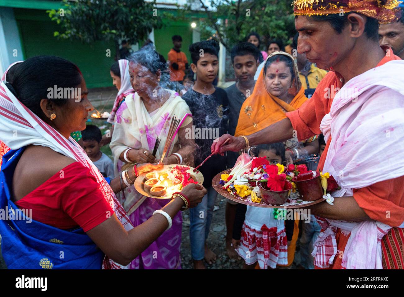 Familie, die vor ihrem Haus steht und Essen anbietet und Kerzen auf Tellern anzündet, Kaziranga, Assam, Indien Stockfoto