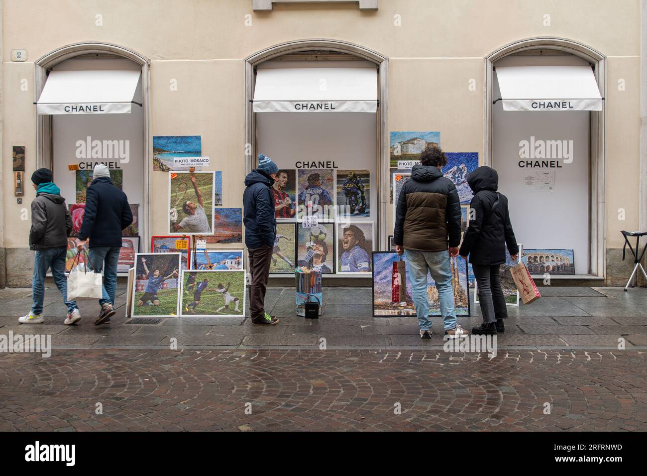 Ein Straßenverkäufer, der im Winter Sportposter vor dem geschlossenen Luxusgeschäft Chanel in der Via Lagrange Street verkauft, Turin, Piemont, Italien Stockfoto