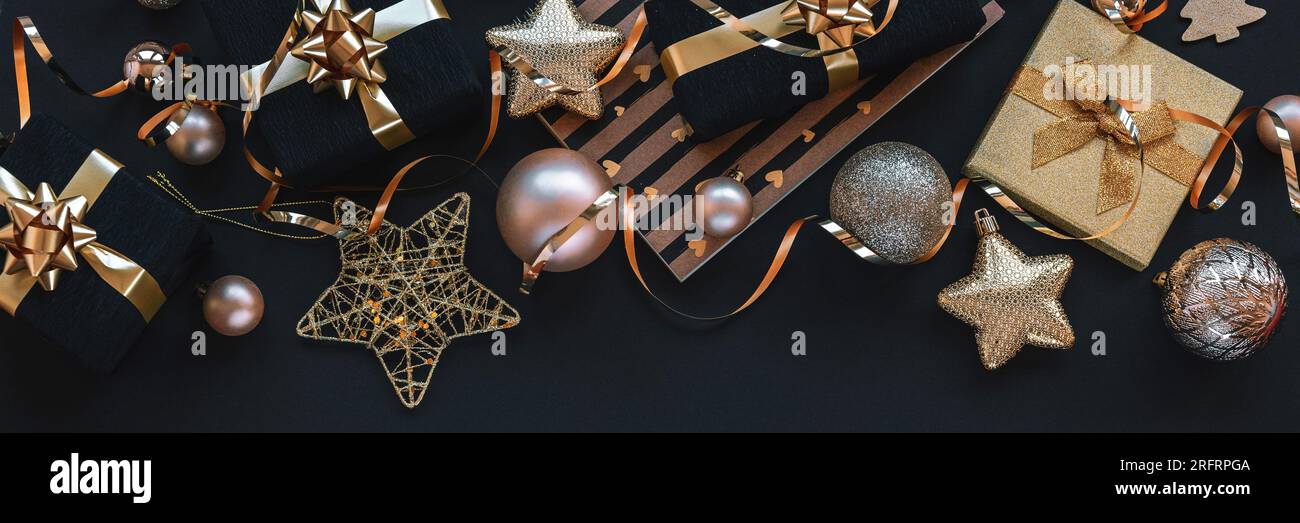 Silvester-Geschenke in schwarzen Boxen, Weihnachtsspielzeug und Girlande auf schwarzem Hintergrund. Draufsicht, flach liegend Stockfoto