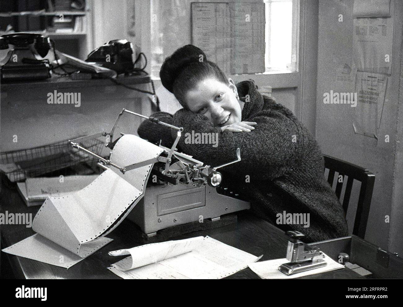 1965, historisch, hartgesottene Arbeit... eine Büroangestellte, die auf ihrer Schreibmaschine ruht, England, Großbritannien. Stockfoto