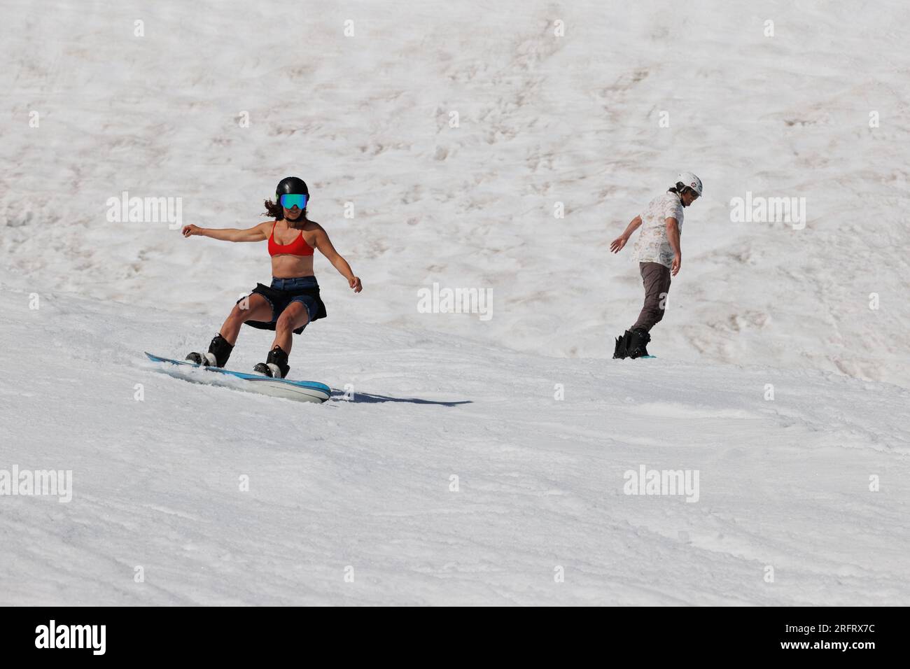 Eine Frau in einem roten Bikinioberteil und blauen Shorts Snowboards am Mammoth Mountain am 4. Juli 2023. Stockfoto