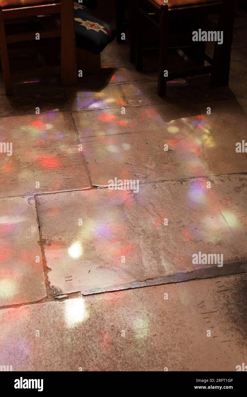 Farbige Reflexionen von Buntglas auf alten Steinplatten, in der Chichester Cathedral in West Sussex, England. Stockfoto