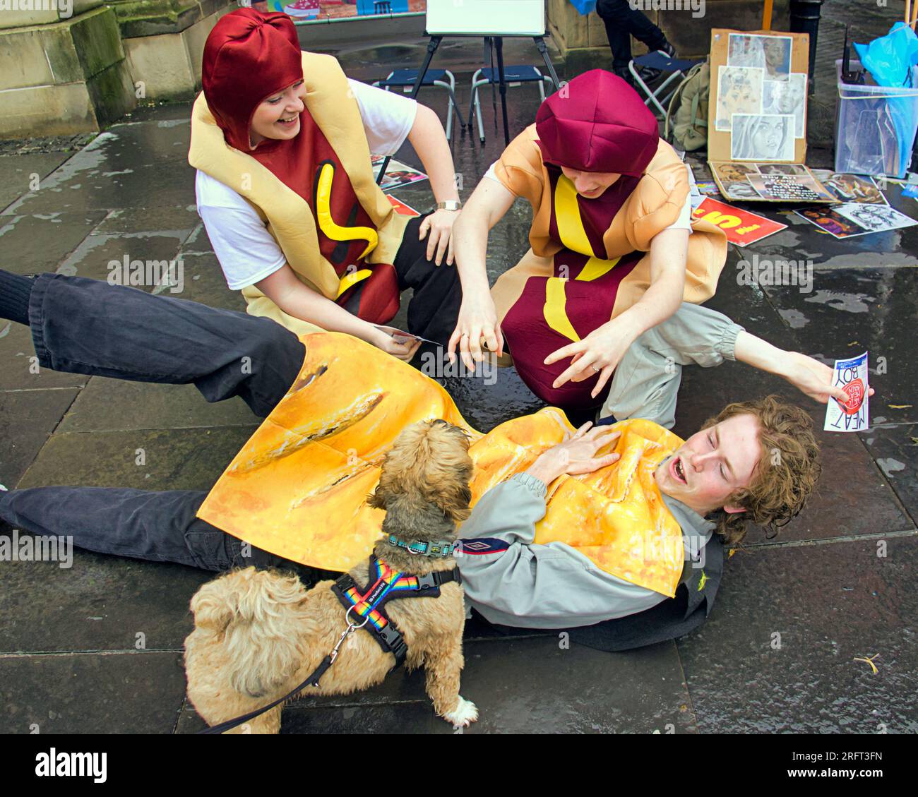 Edinburgh, Schottland, Großbritannien. 5. August 2023. Edinburgh Fringe Künstler waren draußen auf der Royal Mile und haben ihre Shows mit Flyern vor dem Regen angepriesen. Darsteller der Show Meat Boy als Hot Dogs versuchen, ihren Mitspieler, der als Wurstbrötchen verkleidet ist, von einem echten ungarischen Hund, Credit Gerard Ferry/Alamy Live News, zu retten Stockfoto