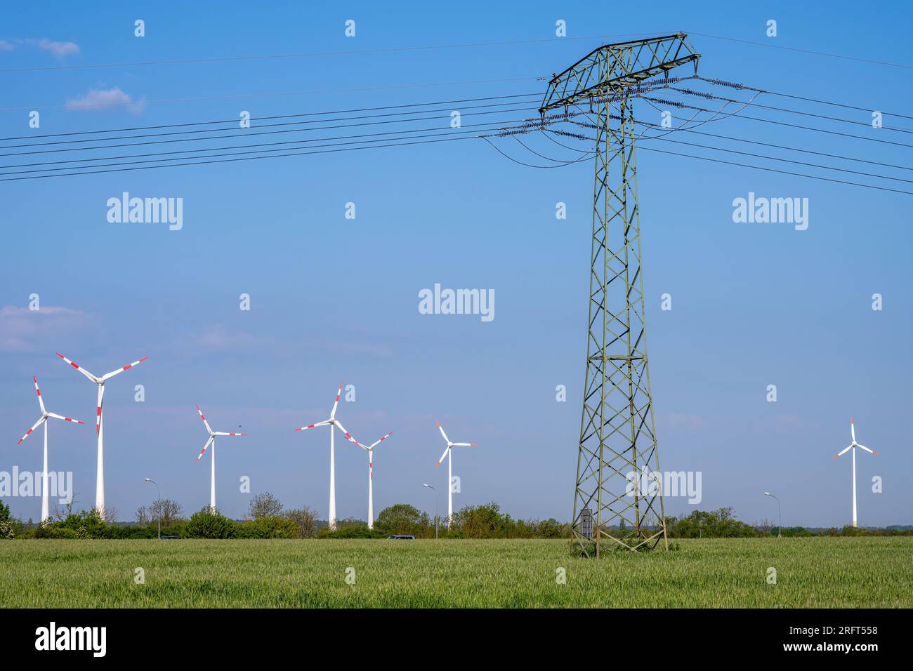 Windturbinen und ein Strommasten mit Stromleitungen in Deutschland Stockfoto