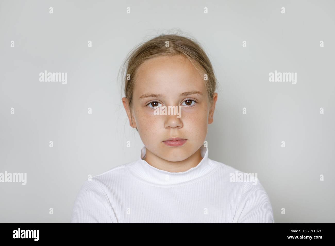 Ein ernstes Mädchen mit weißem Hintergrund, Studioporträt Stockfoto
