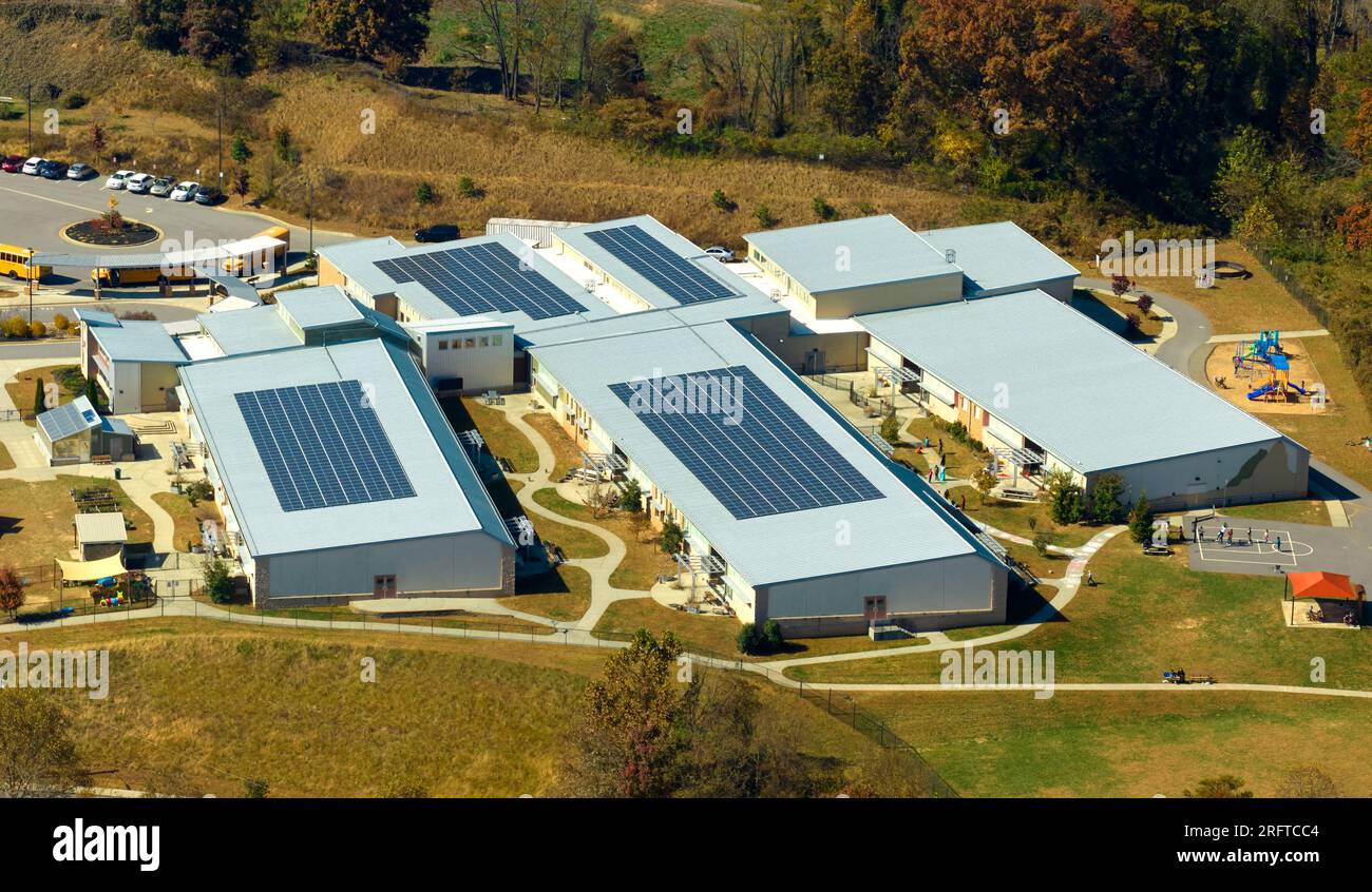 Luftaufnahme des amerikanischen Schulgebäudes auf dem Dach mit Photovoltaik-Solarpaneelen für die Stromerzeugung Stockfoto