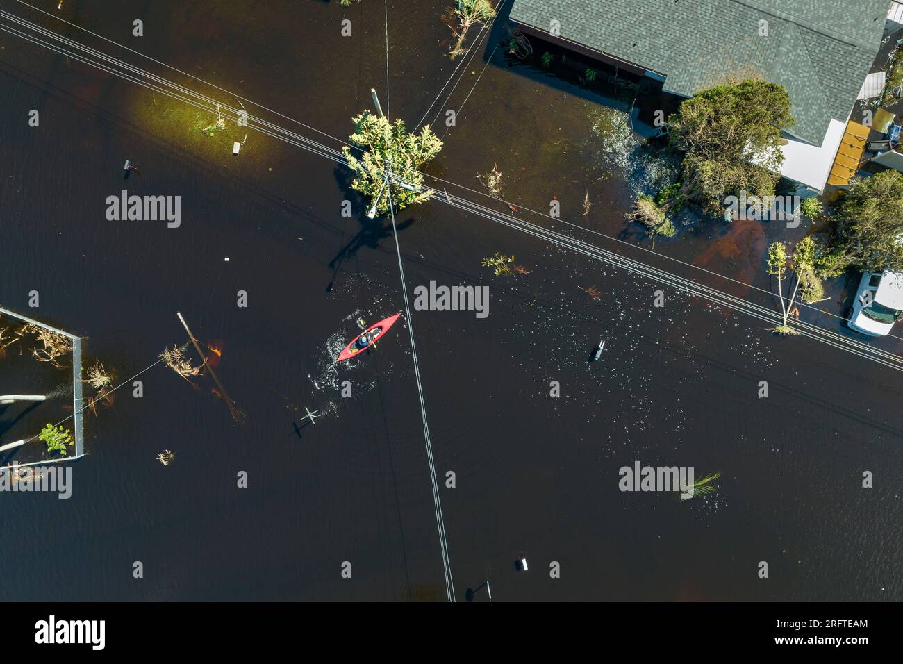 Folgen von Naturkatastrophen. Das Kajakboot schwimmt auf einer überfluteten Straße, umgeben von Hurrikan Ian Regenwasser-Wohnhäusern in Florida Stockfoto