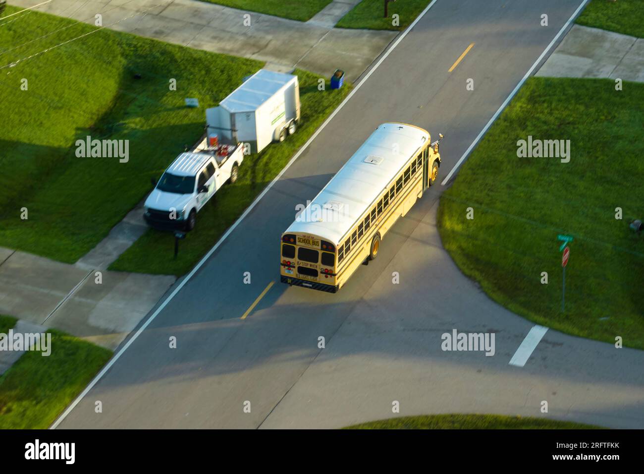 Draufsicht auf den klassischen gelben schulbus der usa, der auf der Straße der ländlichen Stadt fährt, um Kinder für ihre kleinen Kinder am frühen Morgen abzuholen. Öffentlich Stockfoto