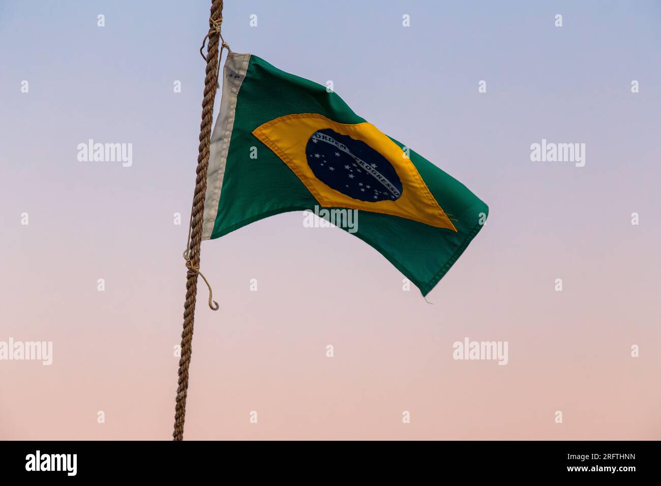 brasilianische Flagge im Freien mit einem wunderschönen farbenfrohen Sonnenuntergang am Himmel von Rio de Janeiro. Stockfoto