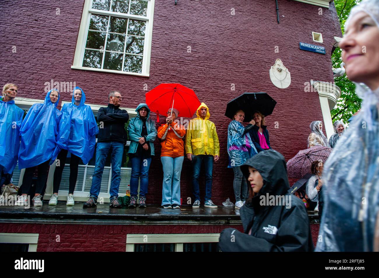 Man sieht, wie sich die Menschen während des Ereignisses von den starken Regenfällen abdecken. Die Kanalparade beginnt gegen Mittag und dauert den ganzen Nachmittag. Rund 80 Schiffe verschiedener Organisationen und gemeinnützige Organisationen nehmen an der Veranstaltung Teil. Für die Grachtenparade ist Amsterdam Gay Pride berühmt. Es ist die Krönung ihres zweiwöchigen Festivals, das mehr als 200 Veranstaltungen umfasst. Die Boote starten am Scheepvaart-Museum im östlichen Teil des Stadtzentrums und fahren in Richtung Amstel. (Foto: Ana Fernandez/SOPA Images/Sipa USA) Stockfoto