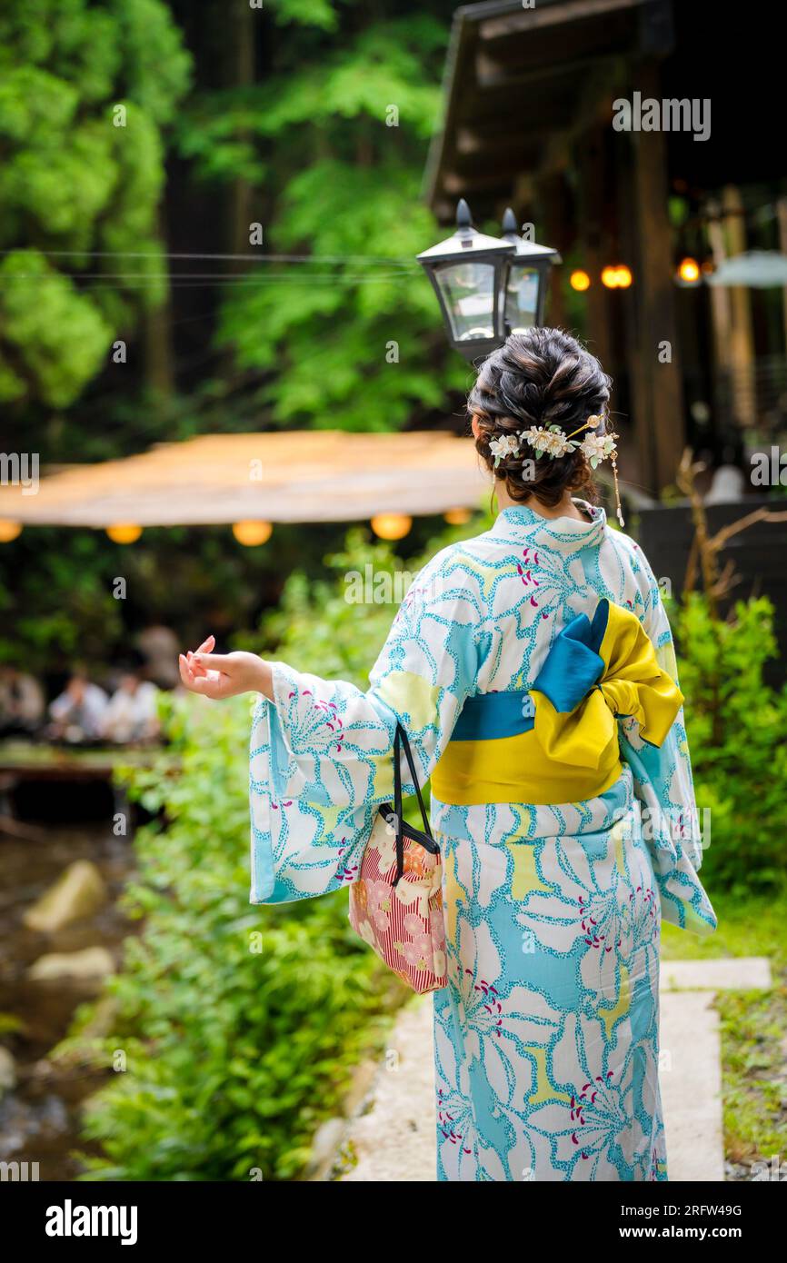 Rückansicht von zwei Frauen mit japanischem Yukata-Sommerkimono, die auf der Straße in der Natur von Kyoto, Japan, spazieren. Stockfoto