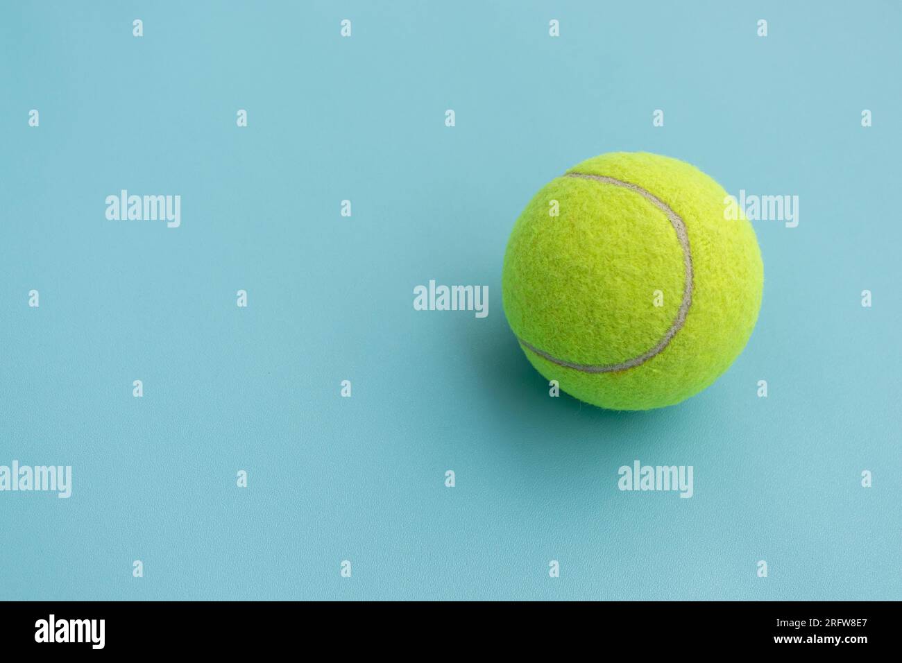 Ein Tennisball isoliert auf blauem Hintergrund, nach einigen Änderungen. Stockfoto
