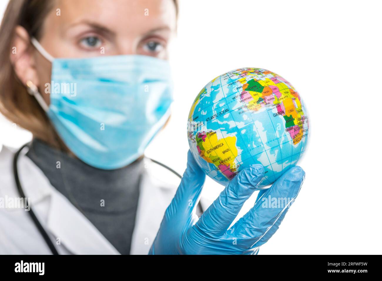 Weibliche Ärztin in schützender medizinischer Maske und Handschuhe hält Globus. Stockfoto