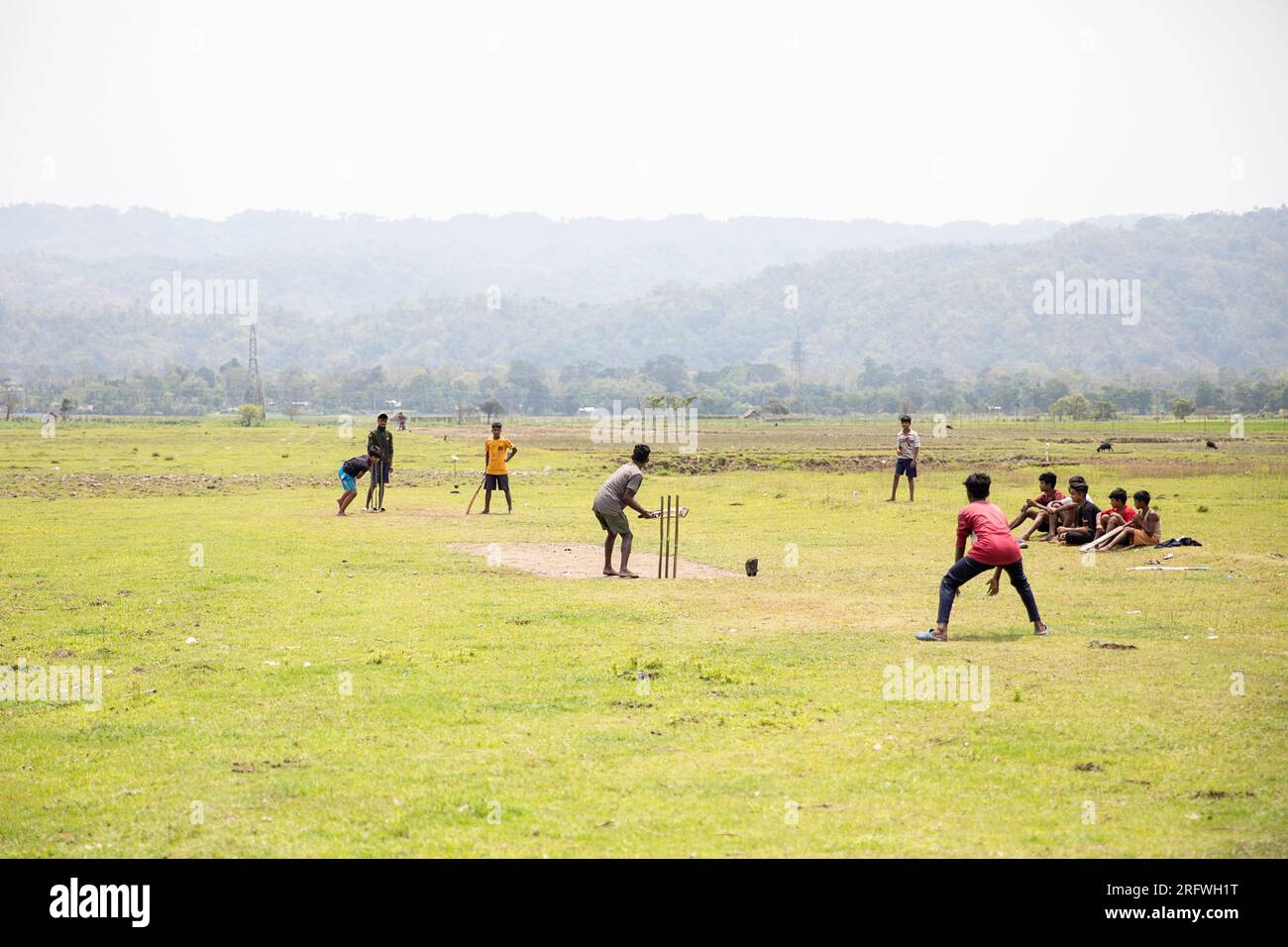 Jungs spielen Cricket auf dem Spielfeld Stockfoto