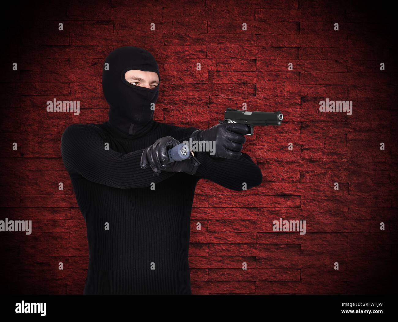 Terrorist mit Pistole auf rote Wand Hintergrund Stockfoto
