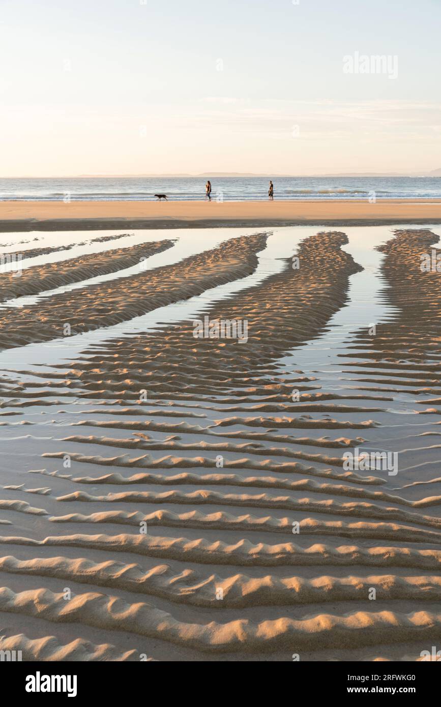 Leute laufen am Kiloran Beach bei Sonnenuntergang, Colonsay, Schottland Stockfoto