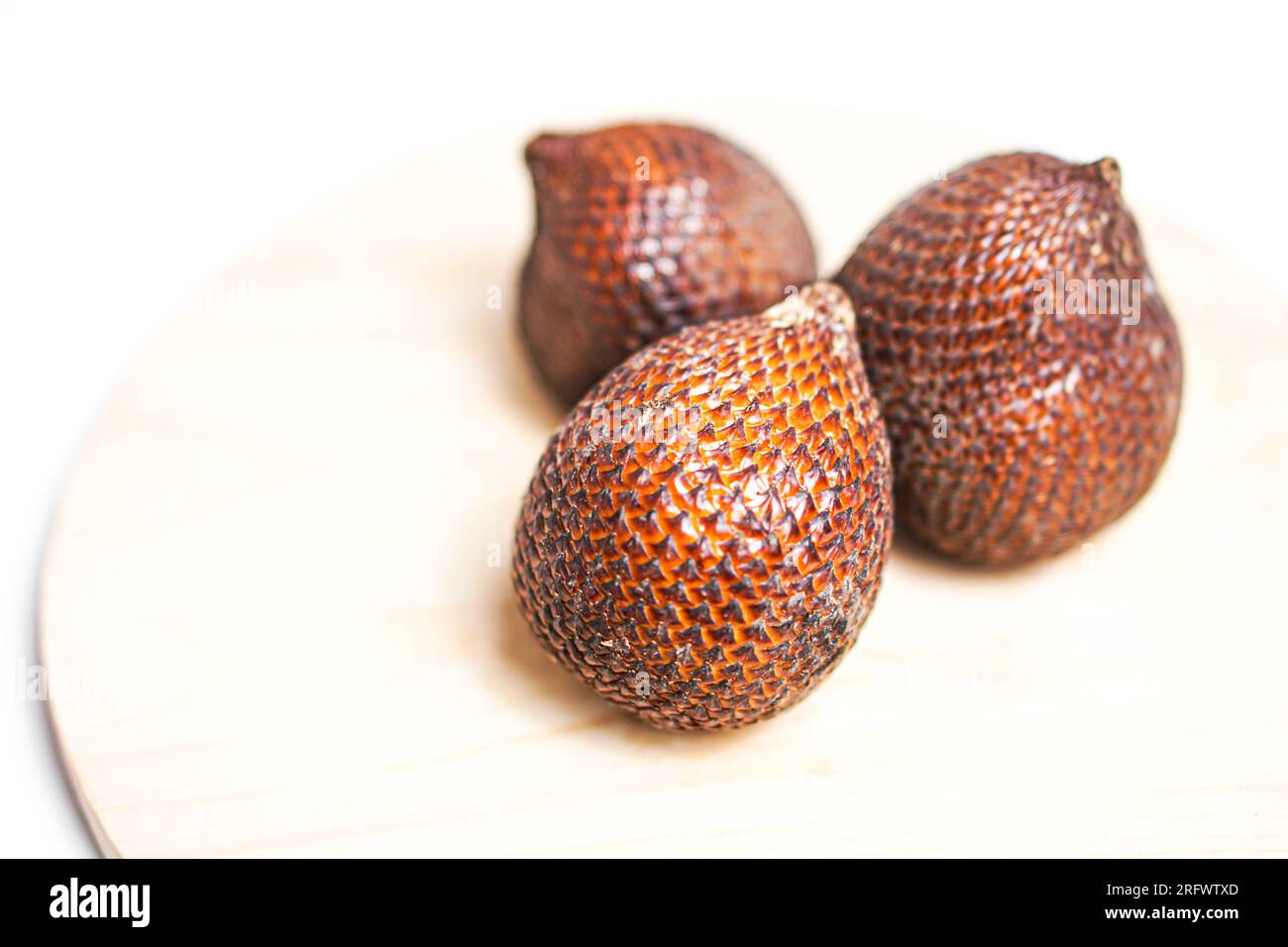 Salak- oder Schlangenfrucht auf Holzplatte isoliert auf weißem Hintergrund. Stockfoto