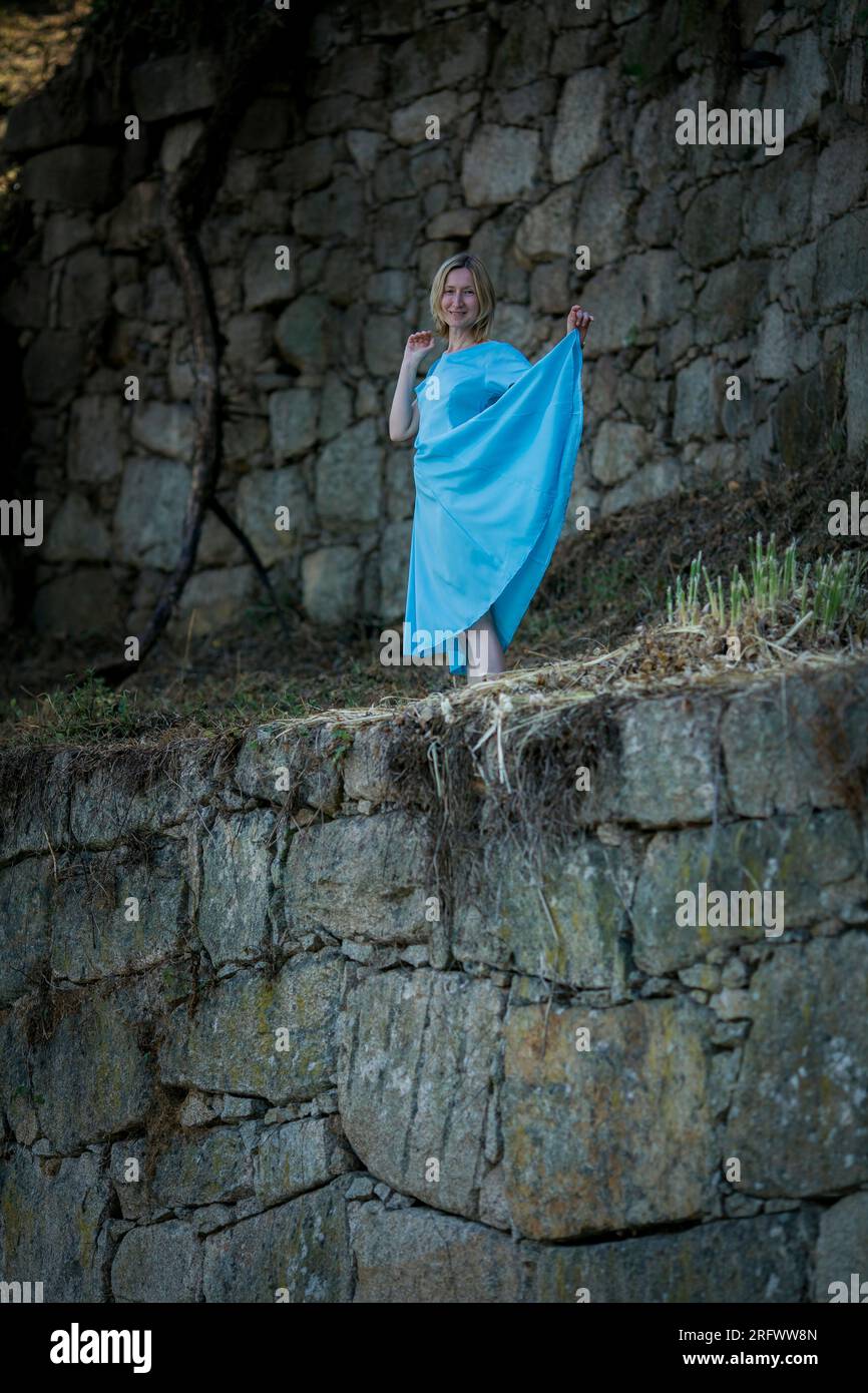 Eine Frau in einem blauen Kleid steht in einer mittelalterlichen Burgruine. Stockfoto