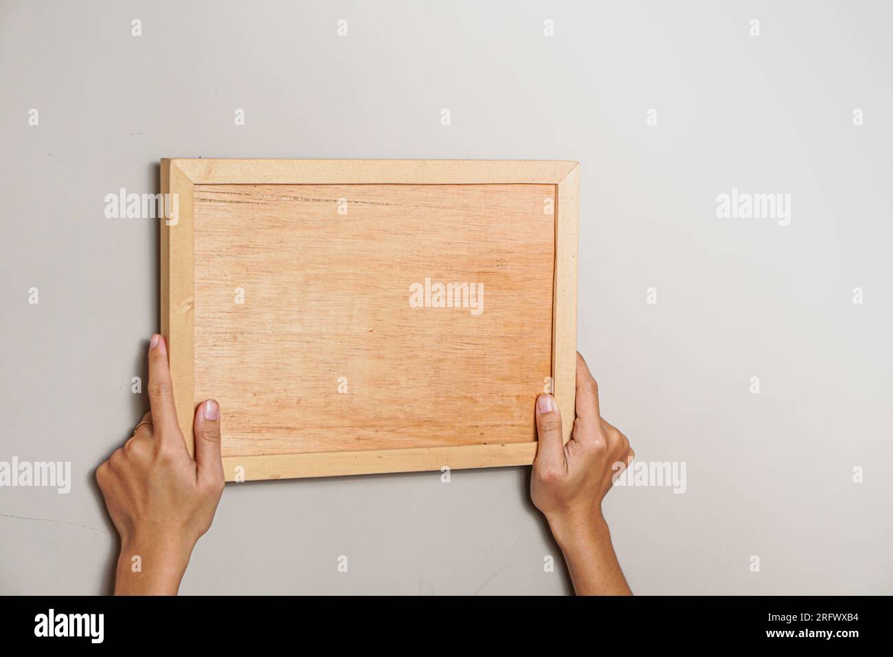 Modell für Ihre Konstruktion. Ein Holzrahmen mit leerem Platz in Frauenhänden Stockfoto