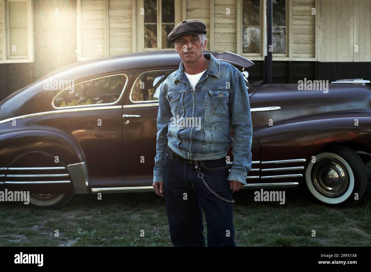 Stilvoller Mann vor einem klassischen Auto im Hotrod Hayride, während Sonnenuntergang, Heathfield, Großbritannien. Stockfoto