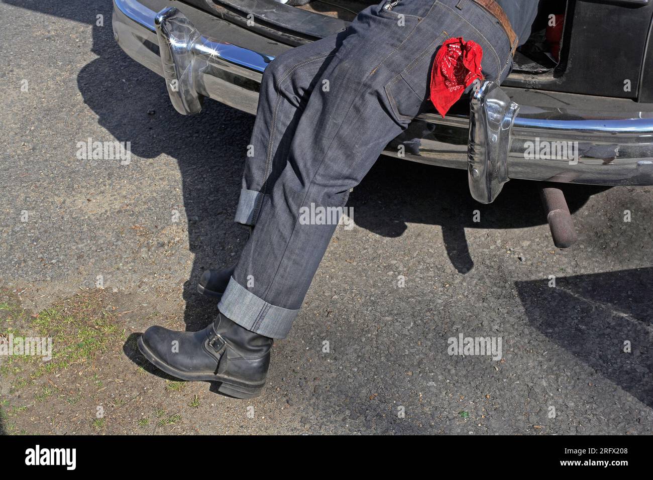 Ein Mann in Jeans, der am Auto arbeitet. Stockfoto