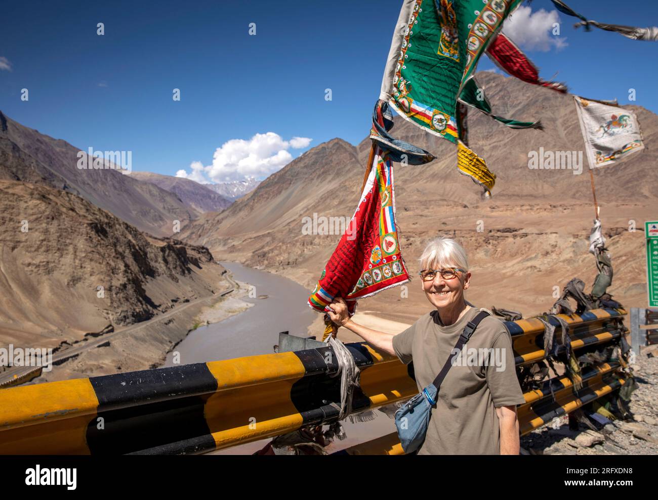 Indien, J&K, Ladakh, Sangam, weibliche Seniorin unter buddhistischer Flagge am Zusammenfluss der Flüsse Indus und Zanskar Stockfoto