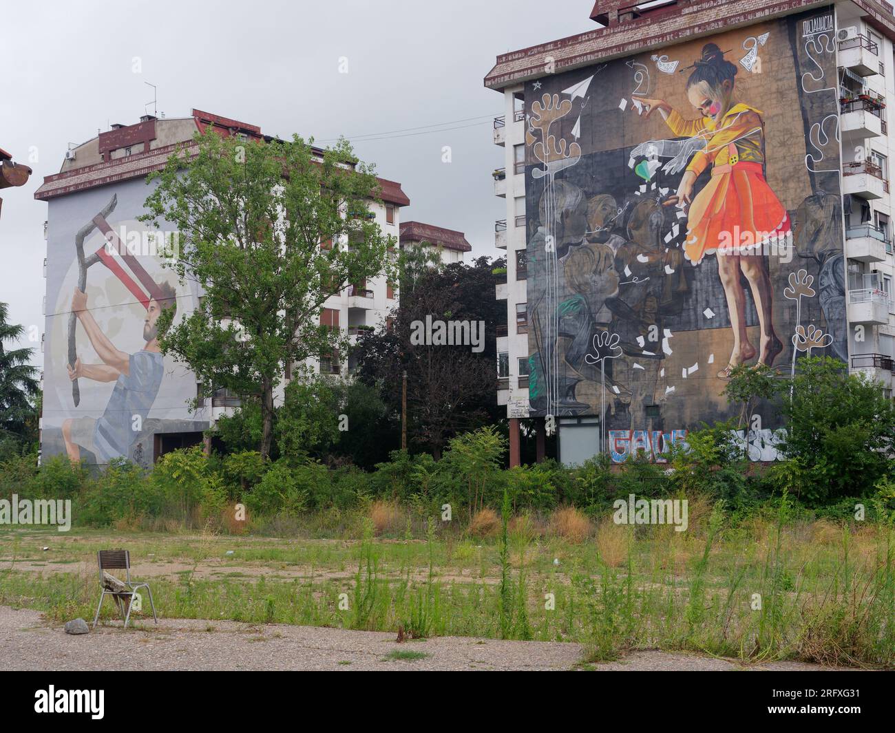 Große bunte Straßenkunst an den Seiten von Gebäuden in der Hauptstadt Belgrad, Serbien. 6. August 2023. Gras wächst im unbehaltenen Vordergrund. Stockfoto