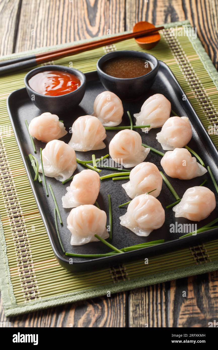 Chinesische har Gow Dim Sum Knödel in Form einer Haube, serviert mit Sauce auf dem Tisch. Vertikal Stockfoto